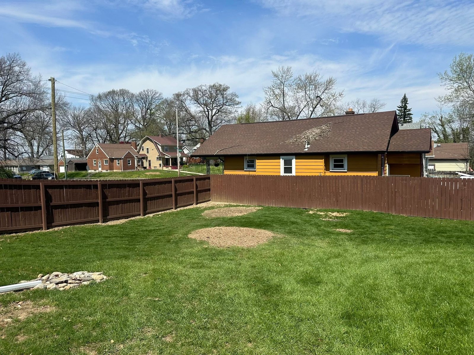 Residential yard after stump grinding with the former stump area covered in chips